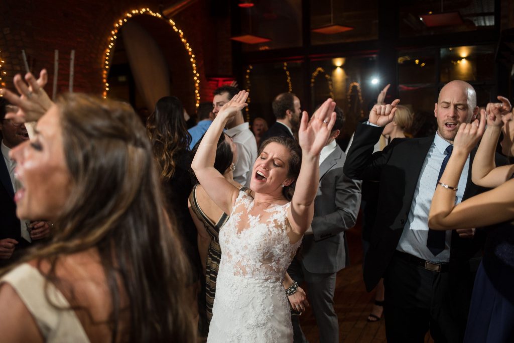 bride with hands raised while dancing
